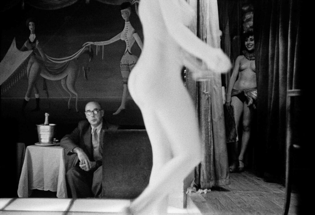 Frank Horvat immortalise le monde du strip tease des années 1950, ici un client du club parisien du Sphinx, une modèle en arrière plan et un corp sculptural au premier plan.