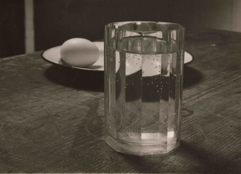 Nature morte avec un verre d'eau et un œuf dans une assiette.