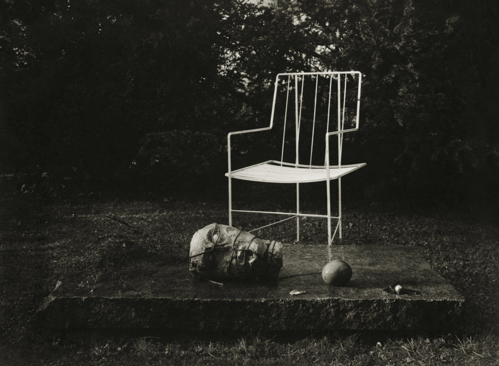 Photographie de Josef Sudek, photographe tchèque, montrant un fauteuil de jardin et une tête sculptée.